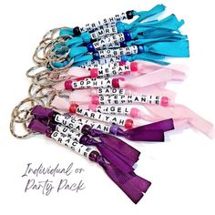 several key chains with words on them and ribbons attached to the ends, all in different colors