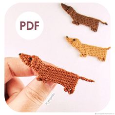 the crocheted dachshund is being held by someone's hand