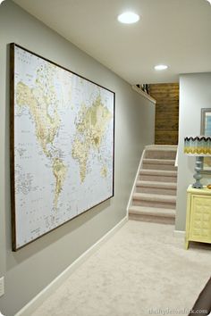 a large map hanging on the wall in a room with carpeted flooring and stairs