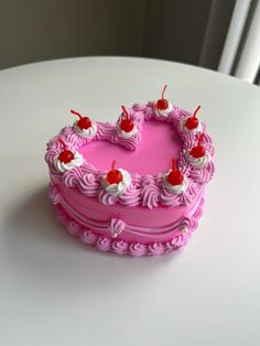 a pink heart shaped cake sitting on top of a white table