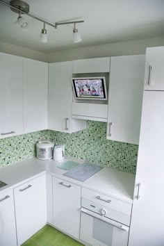 a kitchen with white cabinets and green tile backsplashing on the counter top