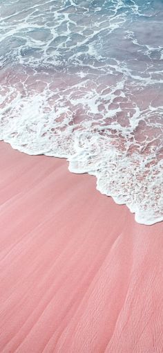 an ocean view with pink sand and waves