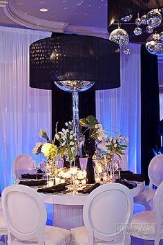 a table with white chairs and chandelier in a room filled with blue lights