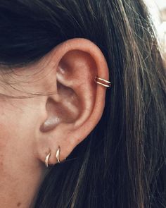 a close up of a person's ear with two small gold hoops on it