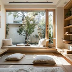 a room that has some pillows on the floor in front of it and a tree outside