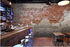 the interior of a restaurant with exposed brick walls and tables, chairs, and bar stools