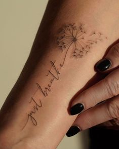 a woman's wrist with a dandelion tattoo on it that says, thank you