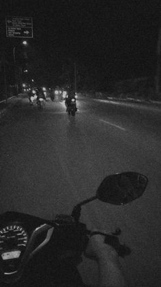 motorcyclist riding down the road at night in black and white with headlights on