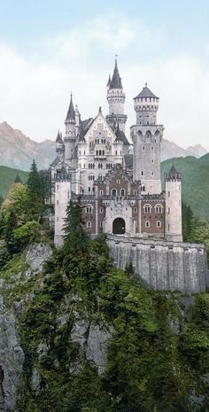 an old castle sitting on top of a mountain surrounded by trees and mountains in the background