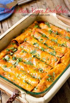 an enchilada dish in a green casserole dish on a wooden table