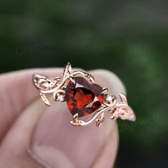 a close up of a person's hand holding a ring with an orange stone