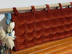 a bench that has some flowers on it next to a red velvet headboard with white and blue tulips