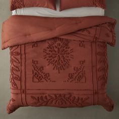 an orange comforter and two pillows on a bed