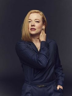 a woman in a pinstripe suit poses for a portrait with her hand on her chin