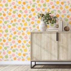 a vase with flowers sitting on top of a wooden cabinet in front of a wall