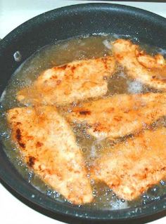 some chicken is cooking in a pan on the stove top with water and oil over it