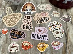 various stickers on a table with coffee cups and mugs in the background that say, let us be happy