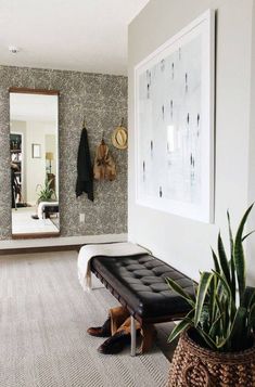 a room with a bench, mirror and potted plant