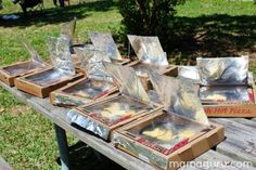 some pizza boxes sitting on top of a picnic table with tin foil wrapped around them