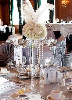 an image of a table setting with flowers and feathers on it's centerpiece