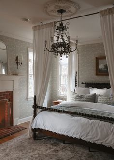 a bedroom with a bed, fireplace and chandelier