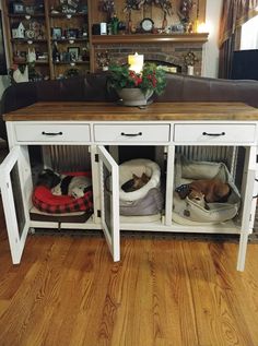 two dogs are sleeping in their beds under the console table, which is also used as a dog bed