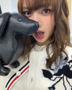 a woman holding a black purse in front of her face