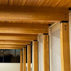 the wooden pillars are lined up against the white wall and windows in the building's exterior