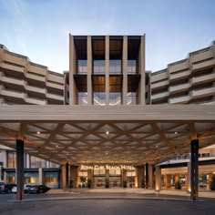 a large hotel building with cars parked in the parking lot and an awning over it