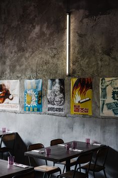 a restaurant with posters on the wall and wooden tables in front of them, along with chairs