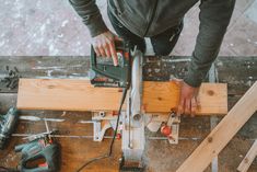 a man using a circular saw to cut wood planks with a cordless jig