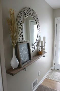 a white vase sitting on top of a wooden shelf next to a mirror and candles