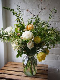 a vase filled with lots of flowers on top of a wooden table