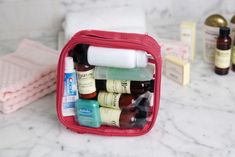 a pink bag filled with lots of different types of beauty products on top of a marble counter