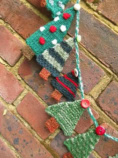 two knitted christmas trees hanging on a brick wall