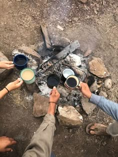 two people are toasting coffee over the campfire with hot dogs and marshmallows