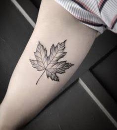 a black and white photo of a leaf tattoo on the left leg, with an outline of a maple leaf