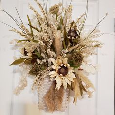 an arrangement of dried flowers in a vase on the front door sill for fall