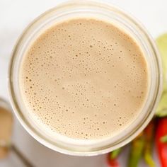 a glass cup filled with coffee sitting on top of a counter next to some peppers