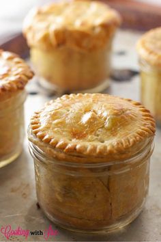 three small pies sitting on top of a table next to each other in glass jars