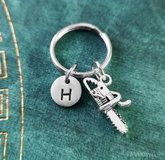 a keychain with the letter h on it is sitting on a green surface