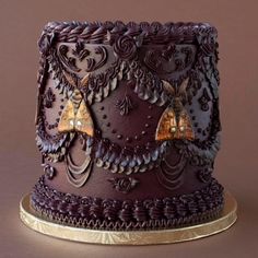 a purple cake with gold decorations on it's sides and brown icing around the edges