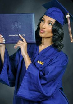 a woman in blue graduation gown holding up her diploma