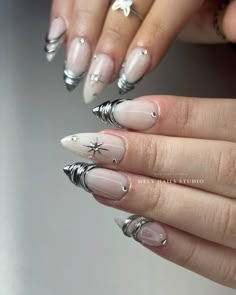 a woman's hand with some white and silver nail polishes on her nails