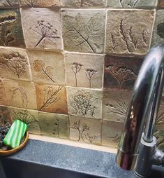 a kitchen sink and faucet in front of a wall with plants on it