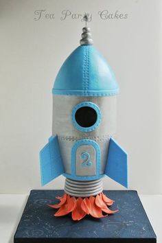 a paper model of a rocket ship sitting on top of a blue mat with an orange flower