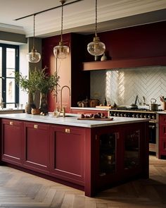 a large kitchen with red cabinets and marble counter tops, along with an island in the middle