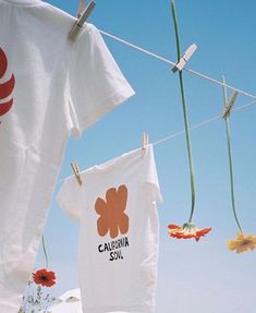 t - shirts hanging on clothesline with flowers in the foreground and blue sky in the background