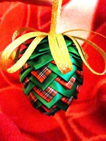 an ornament made out of fabric and ribbon on a red cloth with gold trim