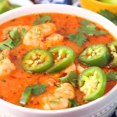 a white bowl filled with shrimp and jalapenos on top of a table